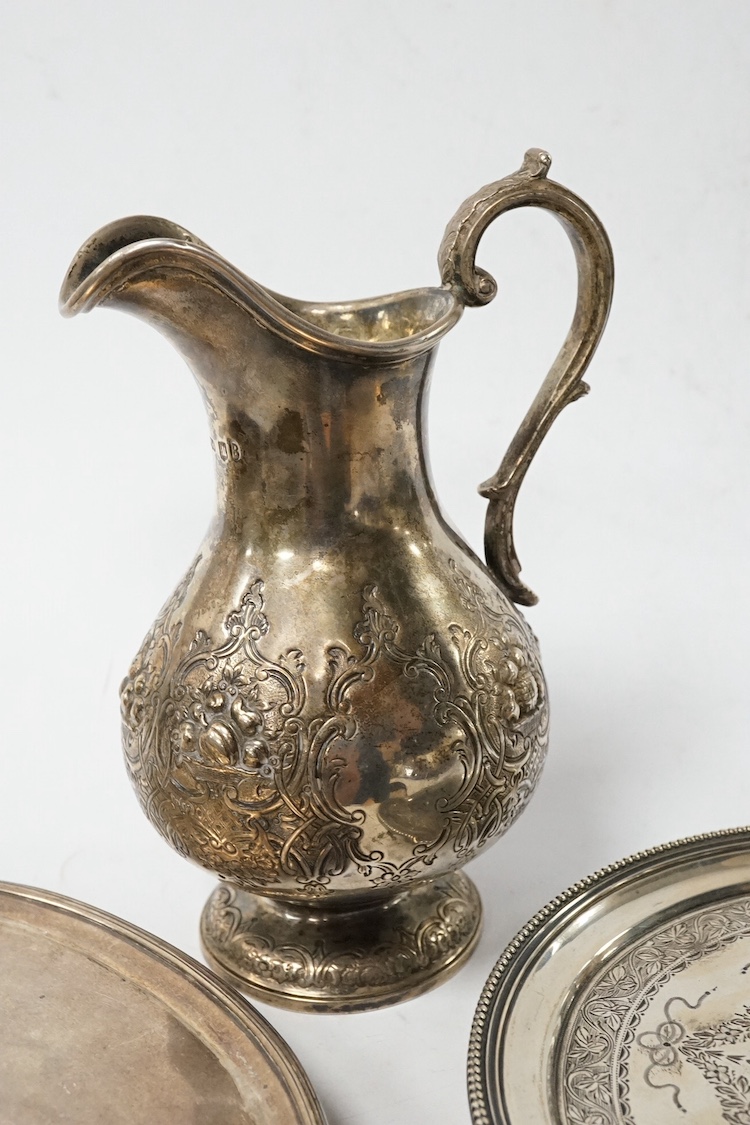 A Victorian Scottish embossed silver cream jug, Marshall & Sons, Edinburgh, 1858, 16.3cm, together with a George III silver oval teapot stand(a.f.), London, 1794 and a Victorian silver waiter, London, 1867, 19.9oz. Condi